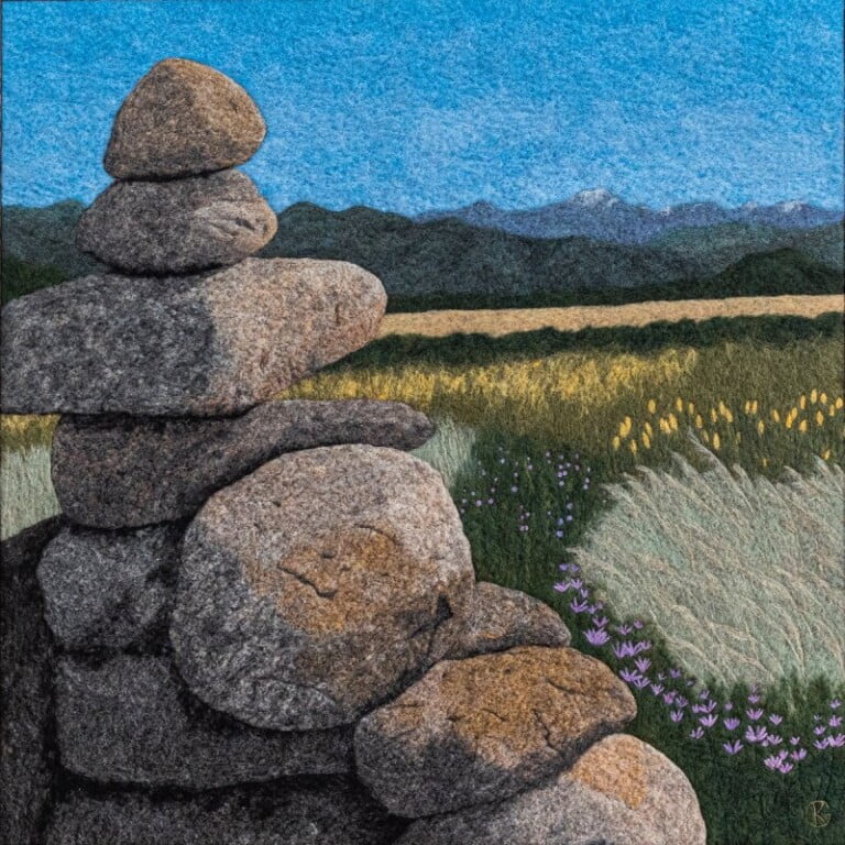Stacked stones with mountain and meadow background.